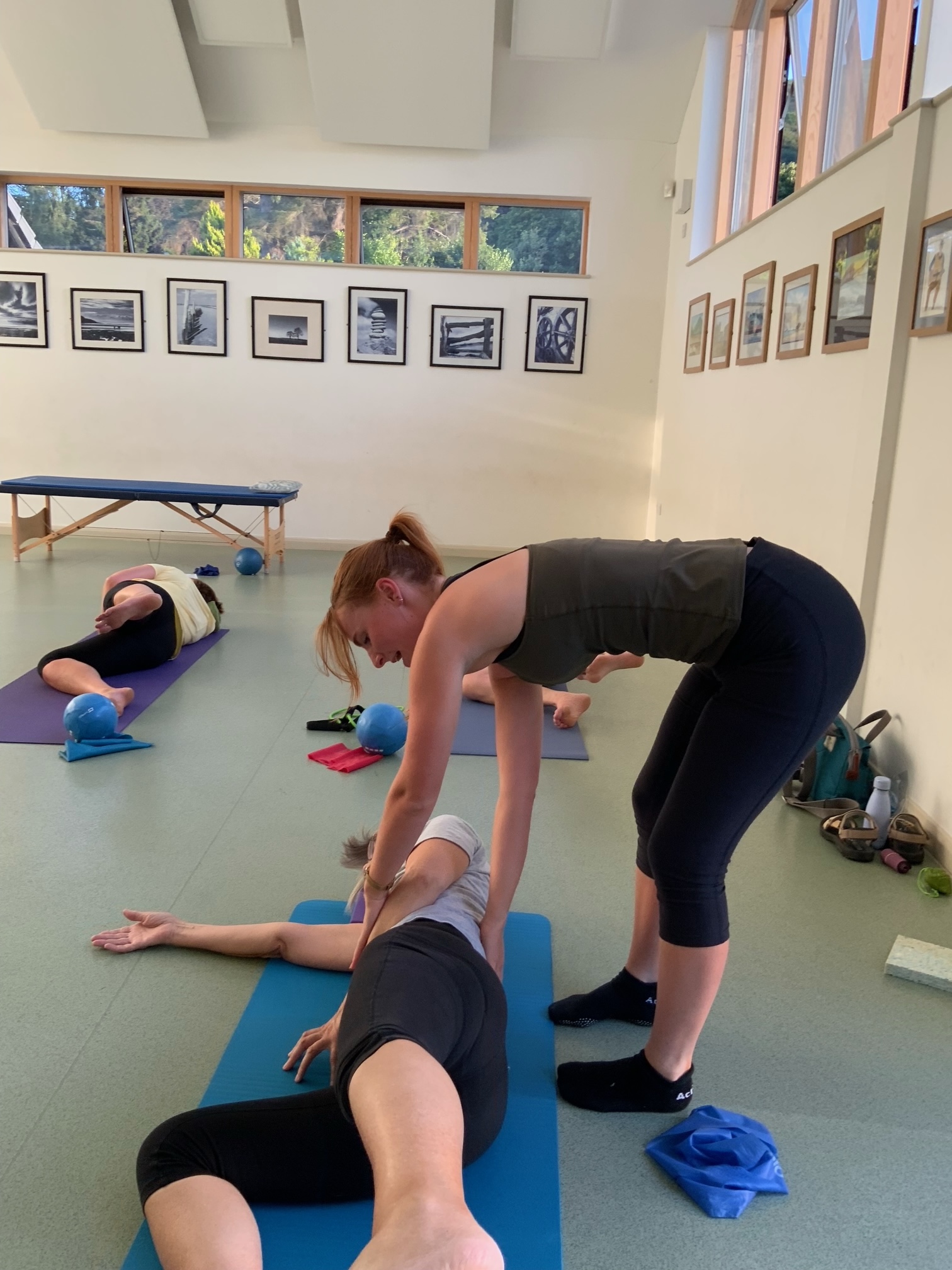 Jess assisting a guest with posture and alignment on the Pilates mat