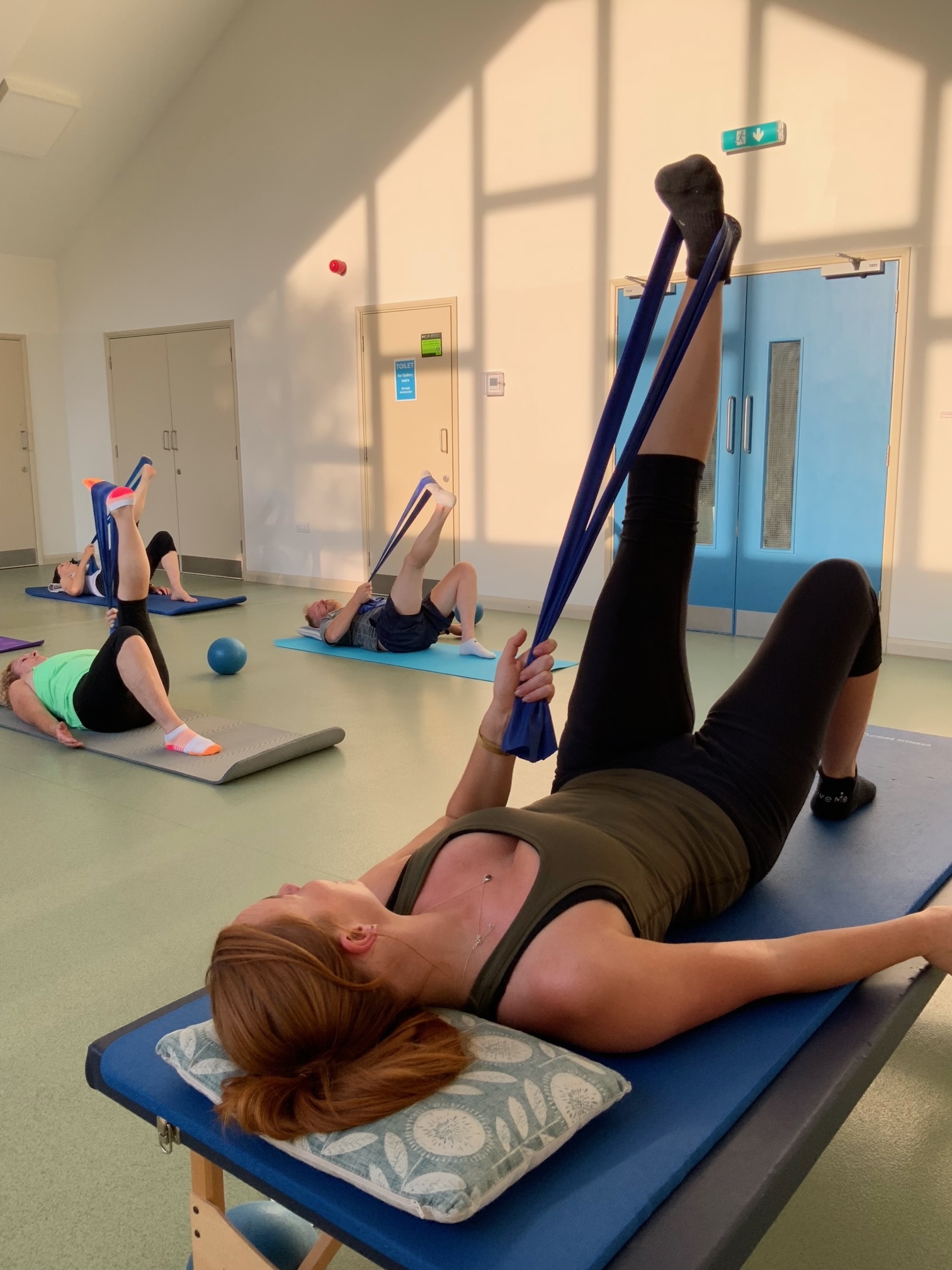 A guest working on mobility and core strength with a resistance band during Pilates